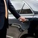 A private driver opening the door of a luxury sedan
